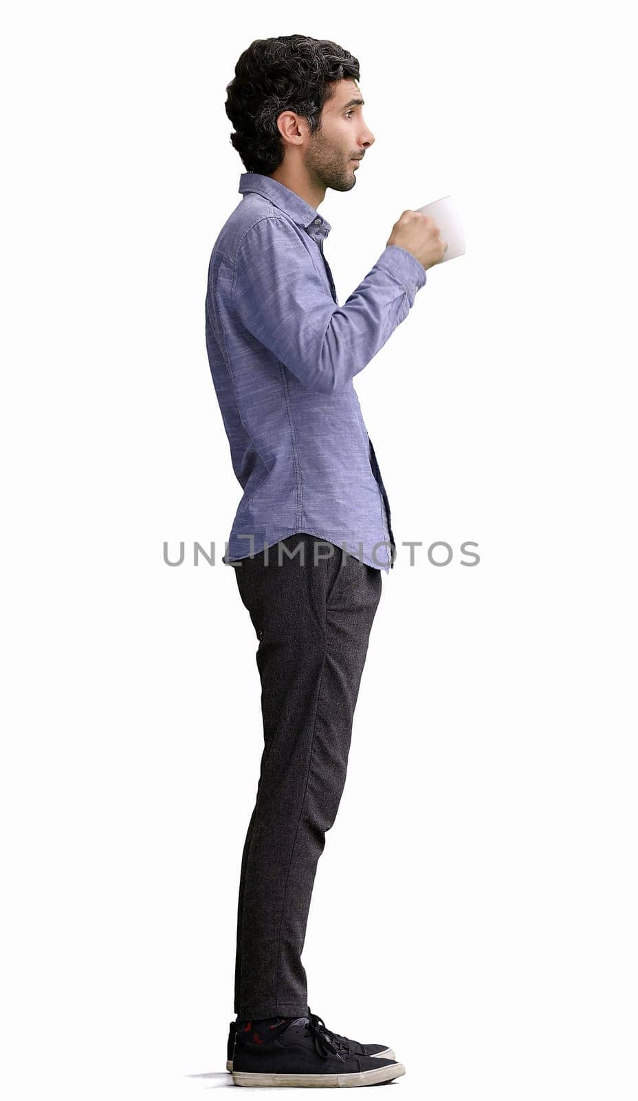 young man in full growth. isolated on white background. holding a mug of coffee.