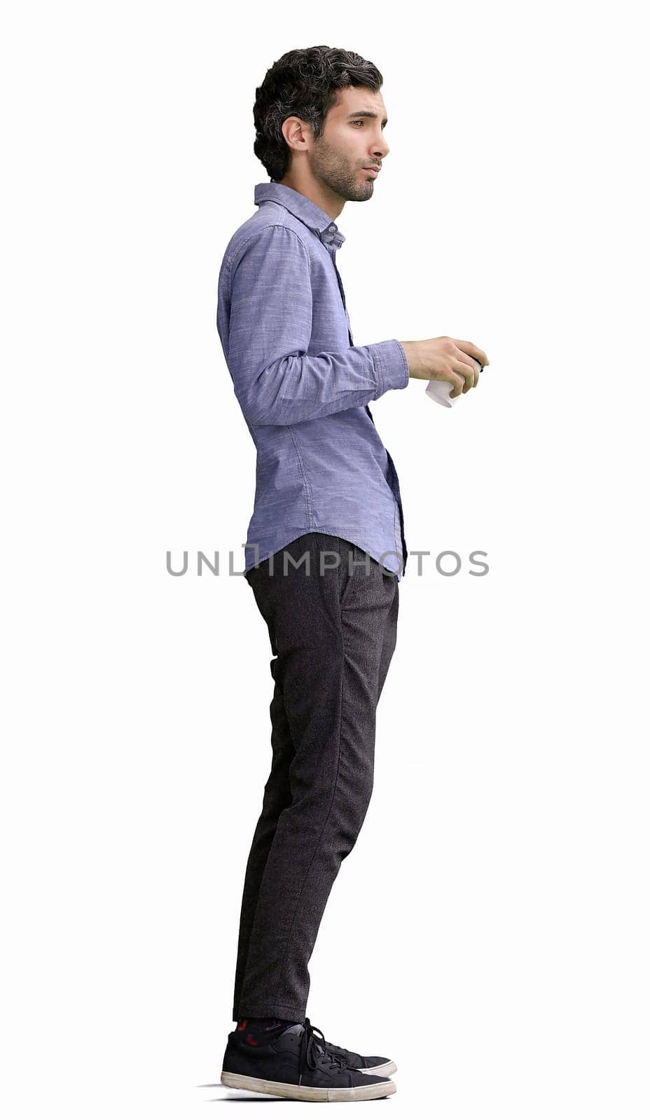 young man in full growth. isolated on white background. holding a mug of coffee.