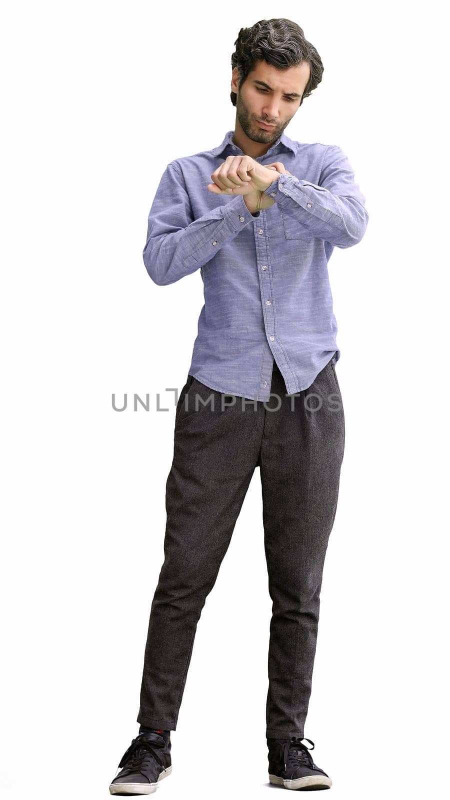 young man in full growth. isolated on white background looking at wristwatch.