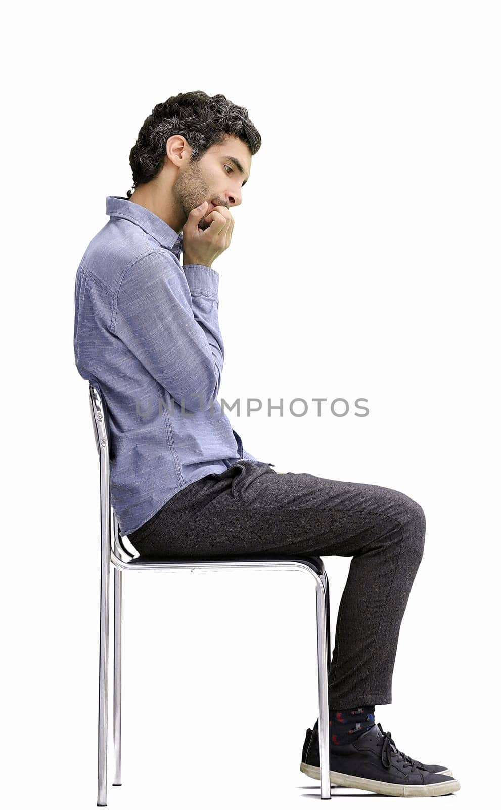 young man in full growth. isolated on a white background sitting on a chair.
