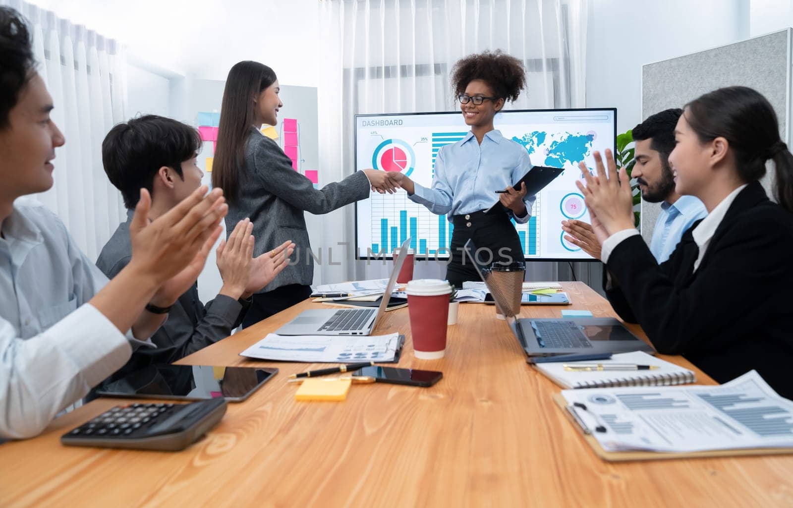 Diverse coworker celebrate with handshake and teamwork in corporate workplace. Happy business people united by handshaking after successful meeting or business presentation on data analysis. Concord