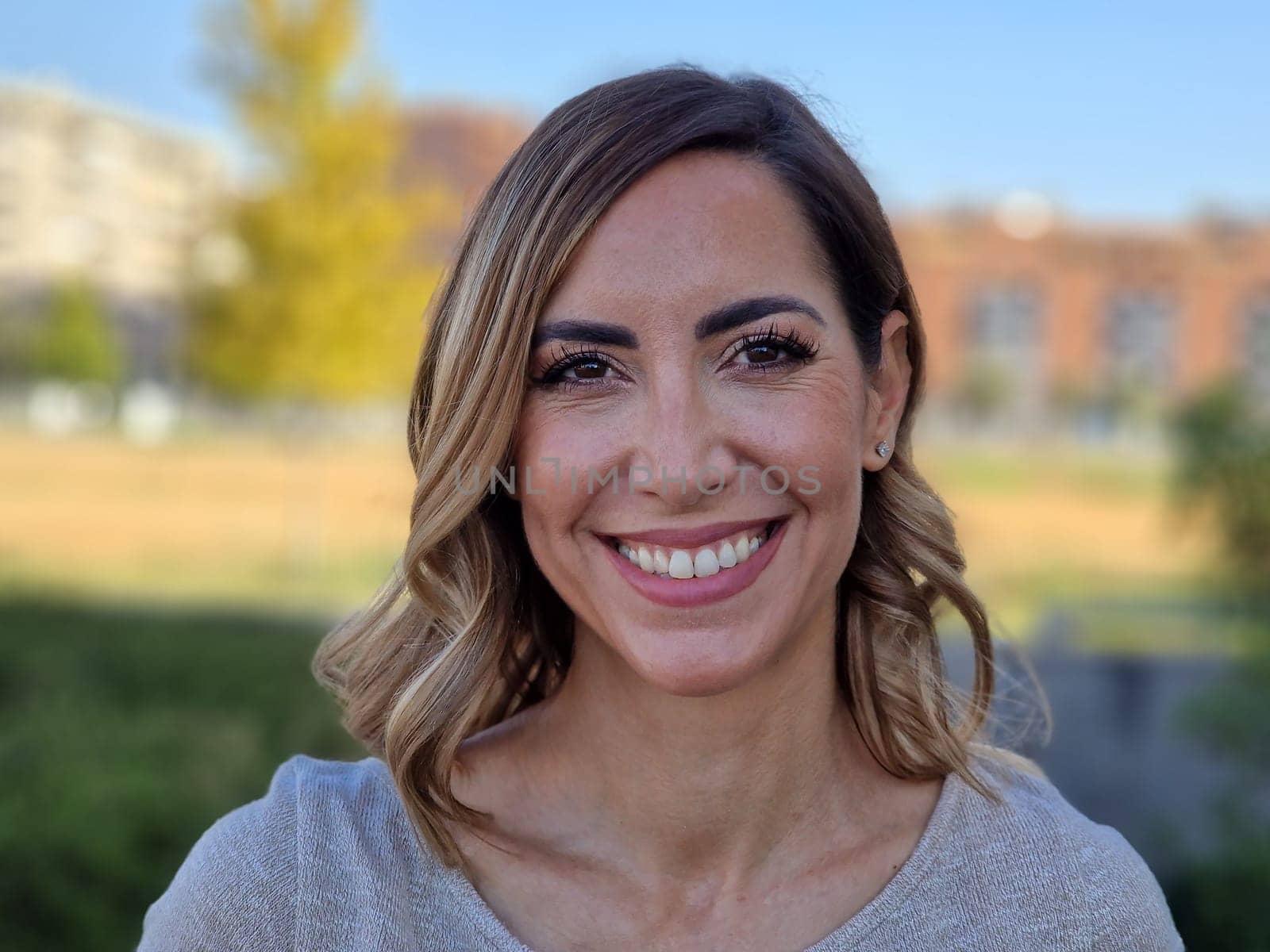 Portrait of a happy middle-aged woman in an urban park. Attractive female smiling to camera.