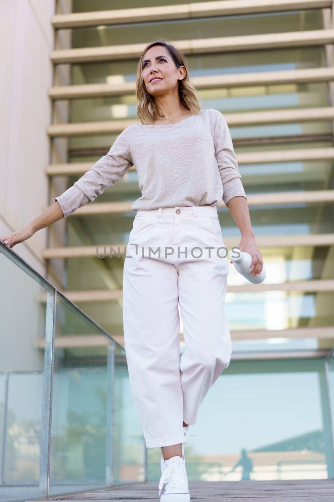 Stylish woman walking on footbridge by javiindy