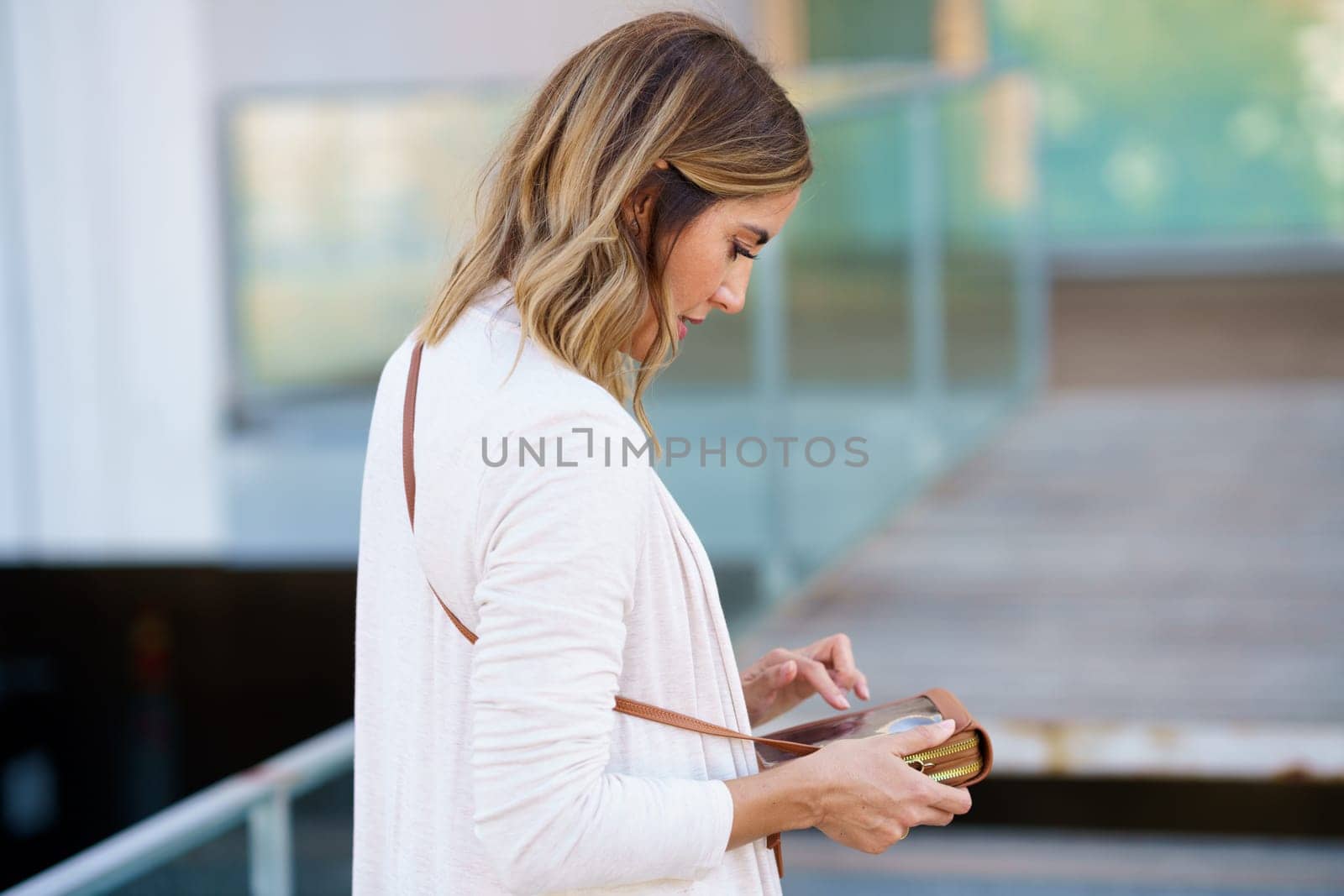 Middle-aged woman using her smartphone through a handbag with space to touch the touch screen. by javiindy