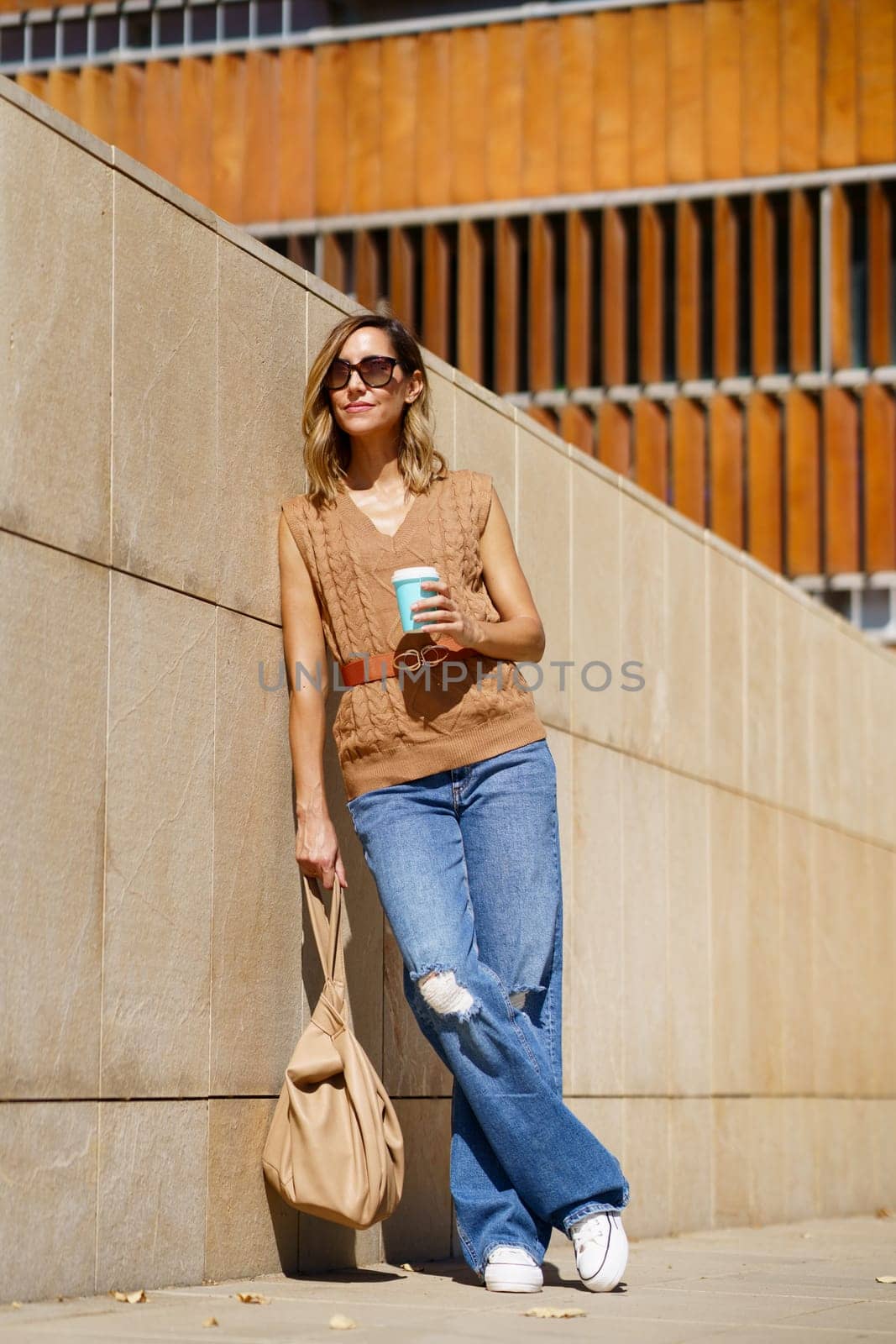 Stylish female with coffee on street by javiindy