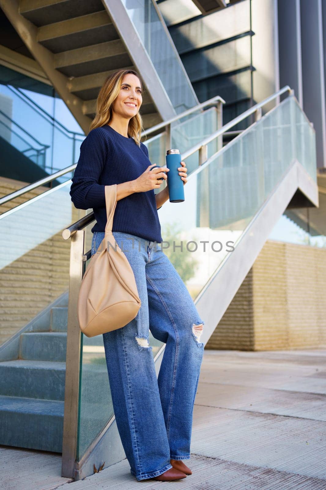 Middle aged female carrying an eco-friendly ecological metal thermos for coffee outdoors by javiindy
