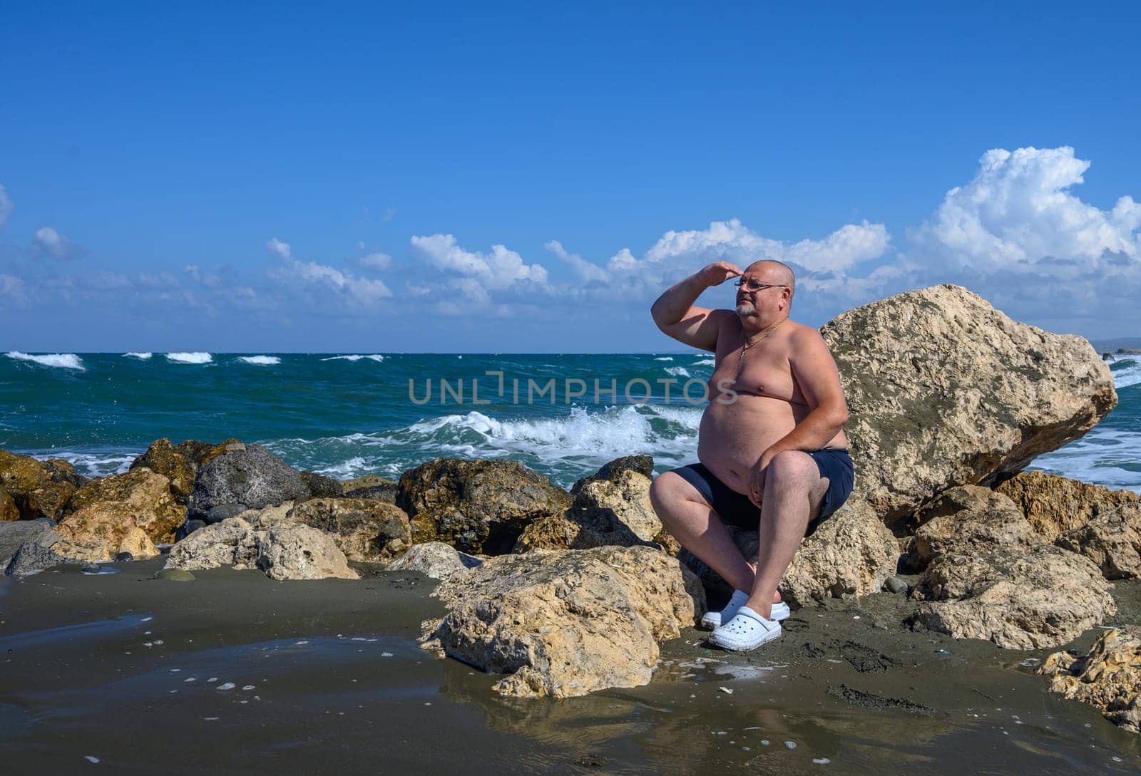 a man looks into the distance sitting on the stones 1