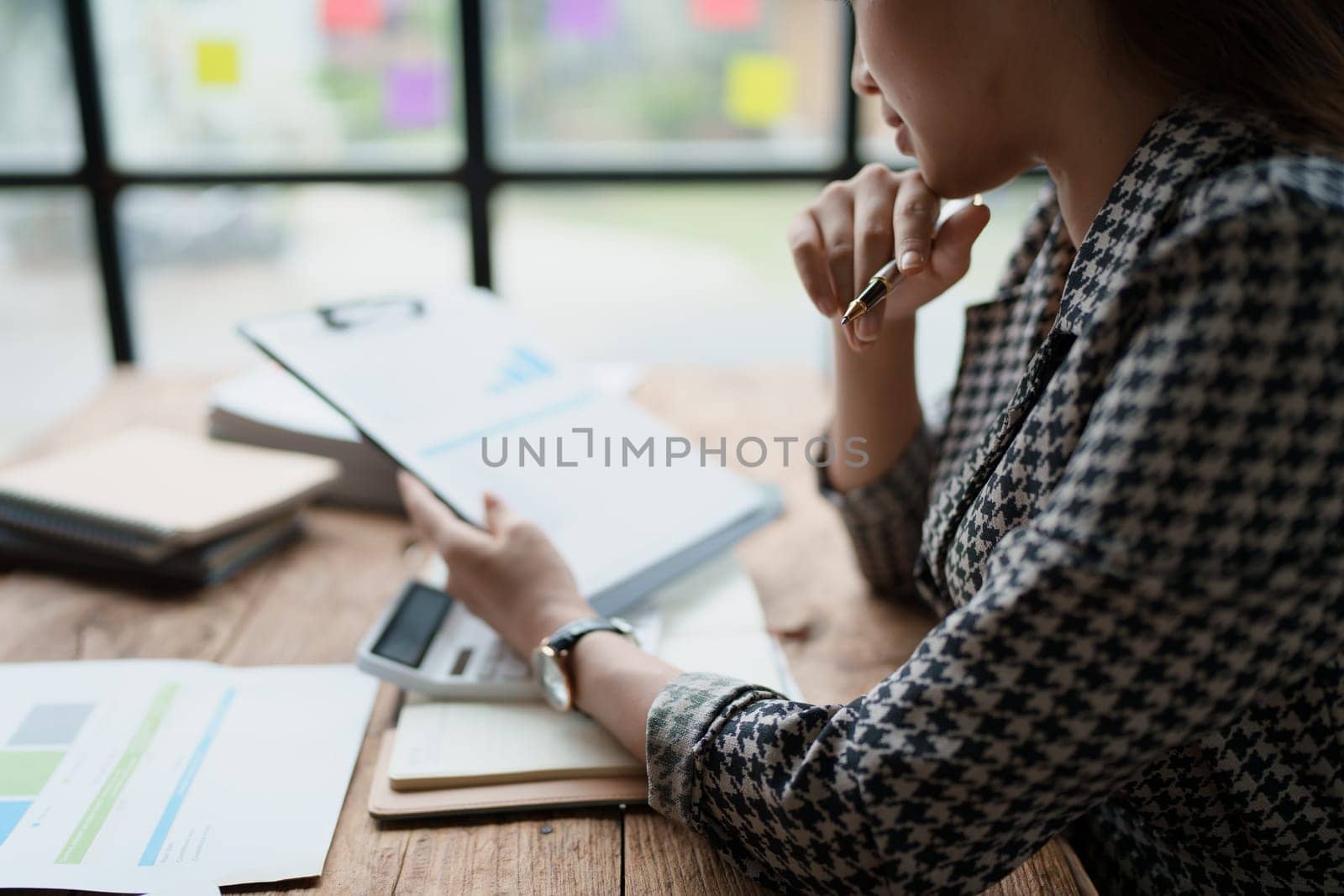 female employee holds a pen and checks investment financial documents. by Manastrong