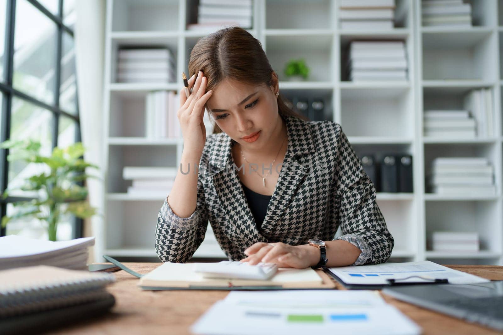 female employee holds a pen and checks investment financial documents. by Manastrong