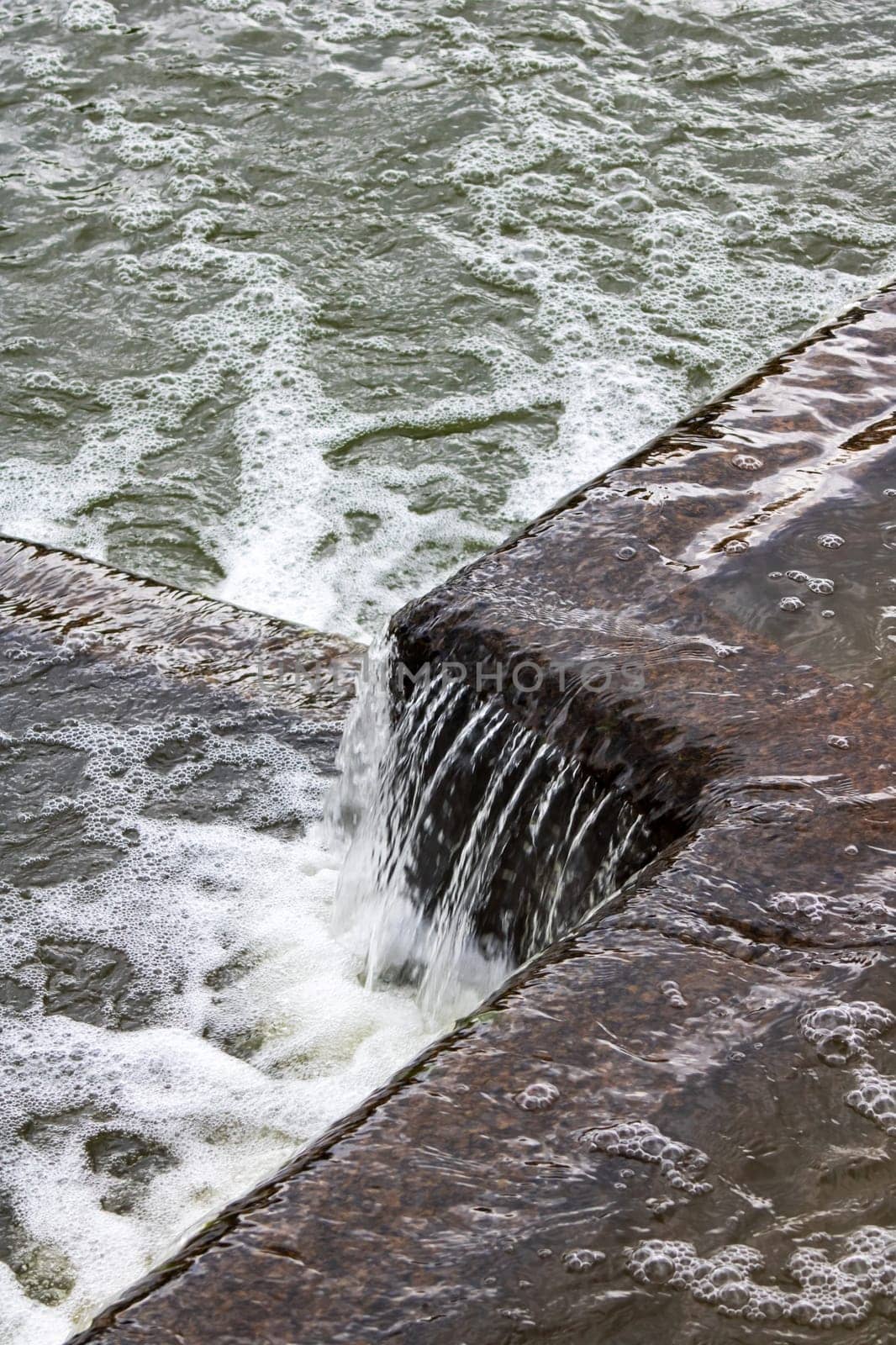 The flow of water in the city waterfall close up