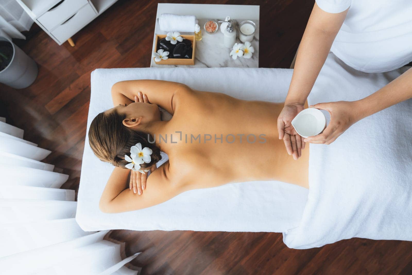 Panorama top view masseur hands pouring aroma oil on woman back. Masseuse prepare oil massage procedure for customer at spa salon in luxury resort. Aroma oil body massage therapy concept. Quiescent