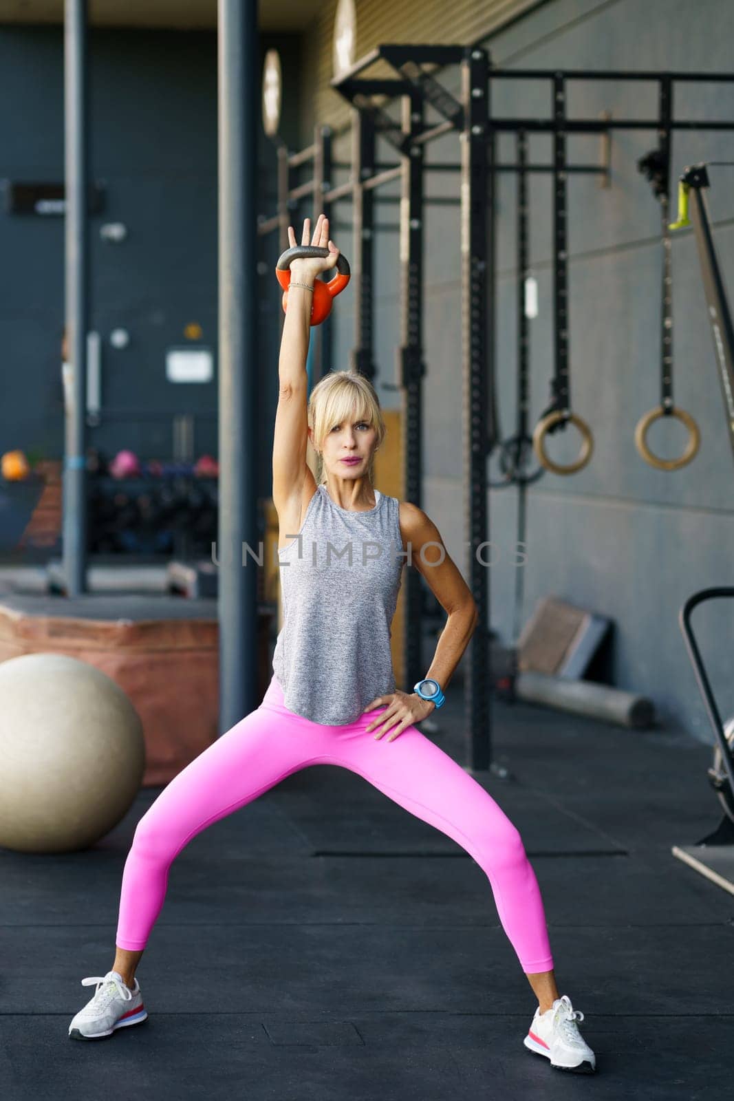 Adult woman doing exercises with kettlebell in gym by javiindy