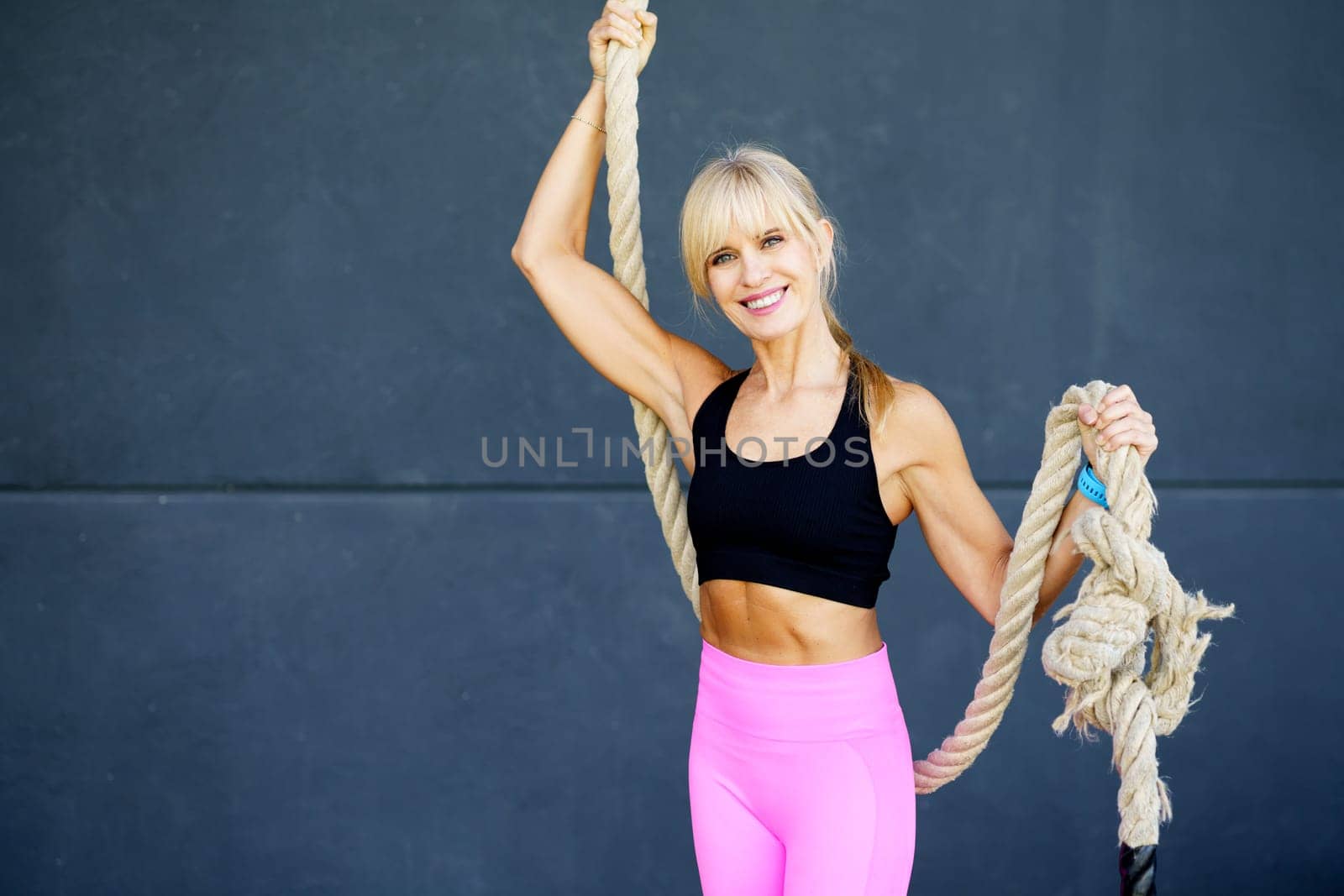 Smiling young woman with rope in fitness studio by javiindy