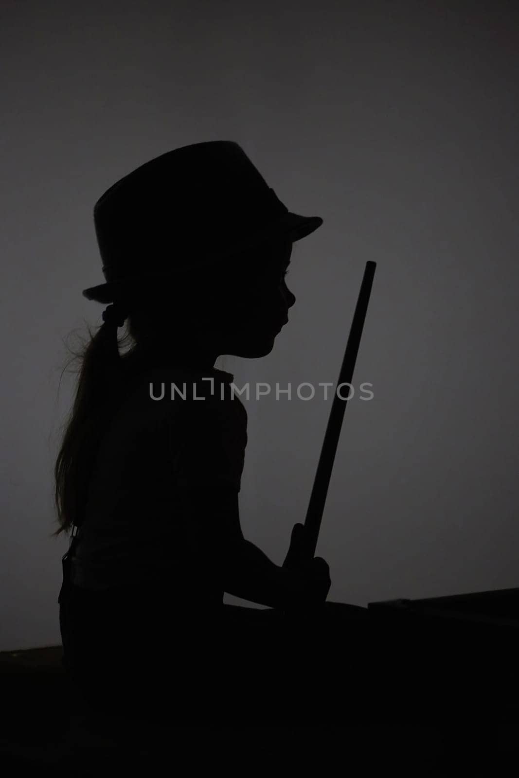 Silhouette of a child playing toy billiards.
