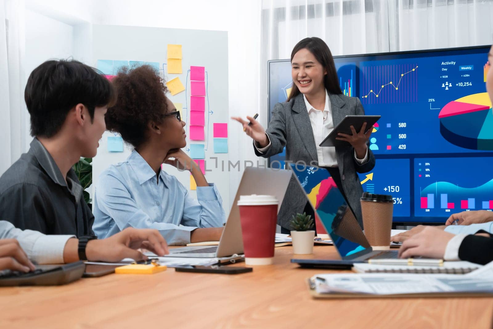 Young asian businesswoman presenting data analysis dashboard on TV screen in modern meeting. Business presentation with group of business people in conference room. Concord