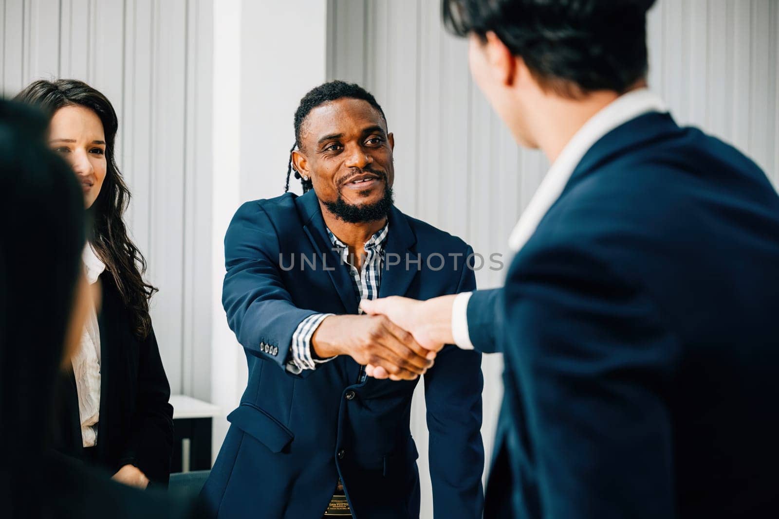 A mature businessman congratulates a younger colleague with a handshake, signifying a successful agreement and partnership during a leadership meeting. Businessmen shake hands as they negotiate.