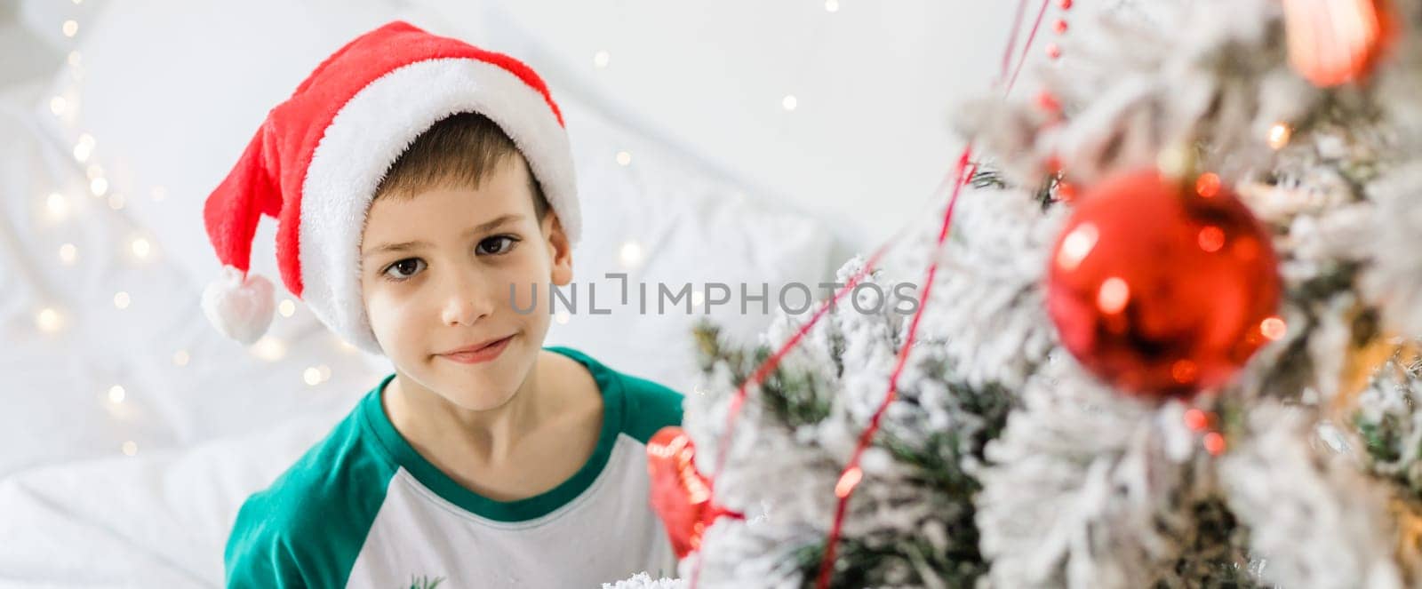 Banner portrait of cheerful boy smiling and laughing next to Christmas tree at house. Families and children generation alpha celebrating winter holidays. Gen alpha, copy space by Satura86