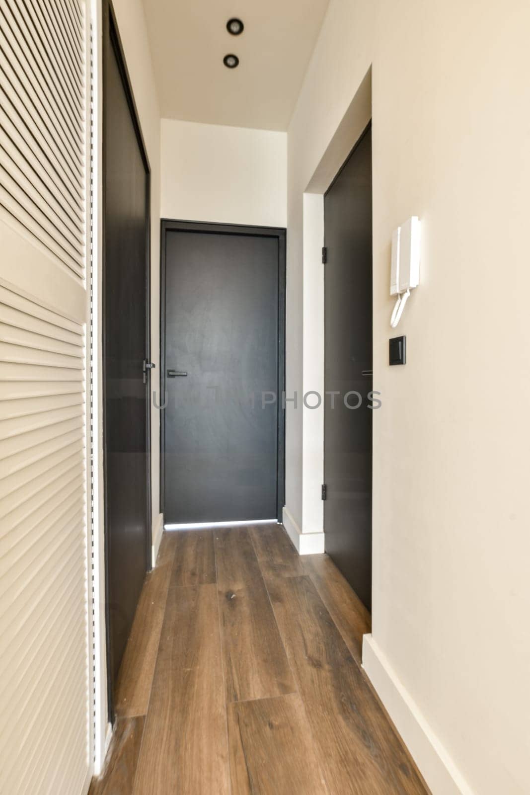 a hallway with a black door and wood flooring by casamedia