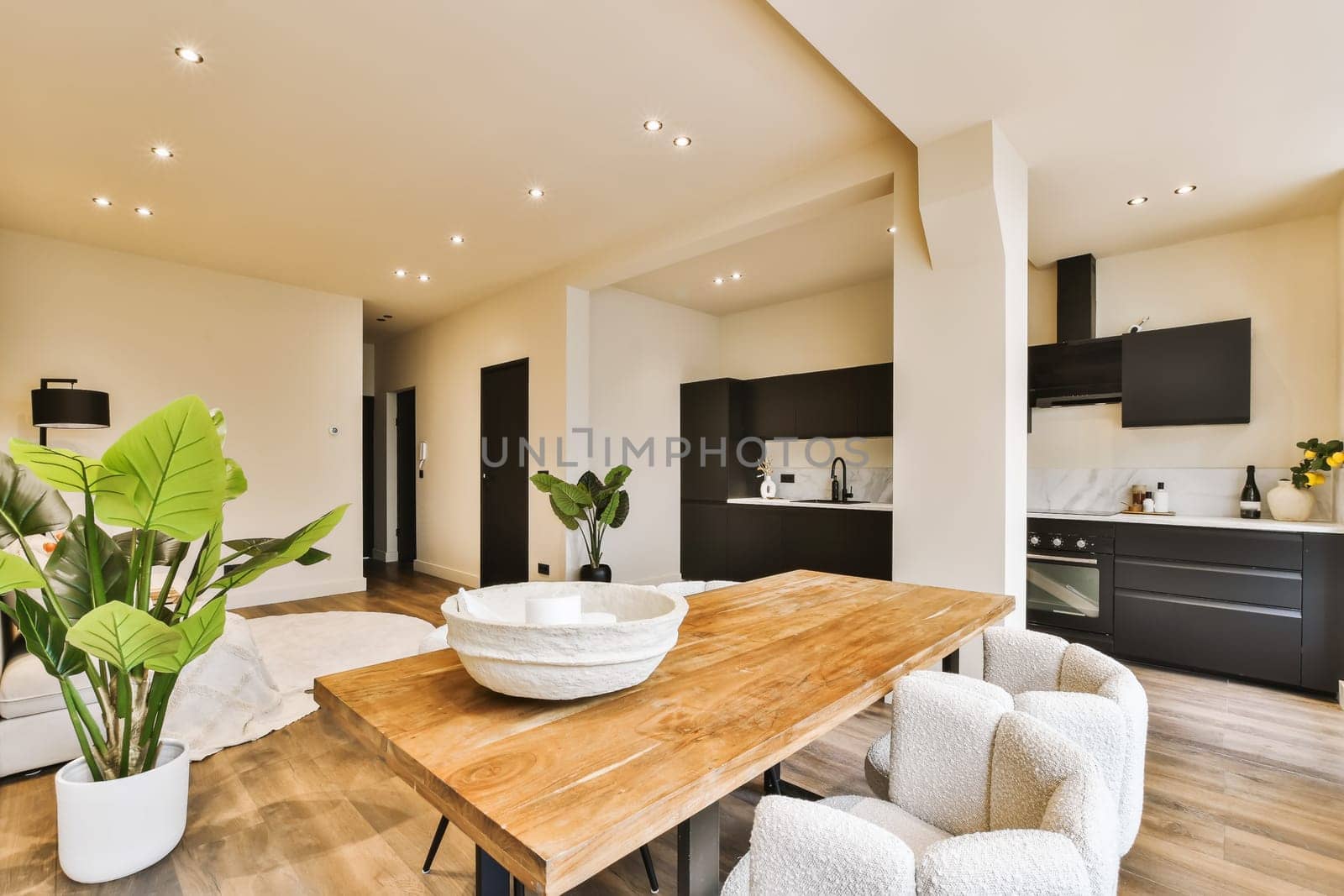 a kitchen and dining area in a modern home with wood flooring, white walls and black cabinetd cabinets