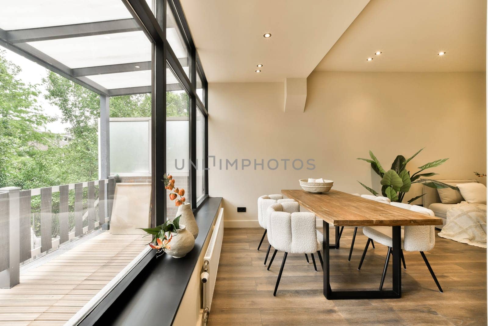 a dining table and chairs in a room with large windows looking out onto the trees that line the side of the house