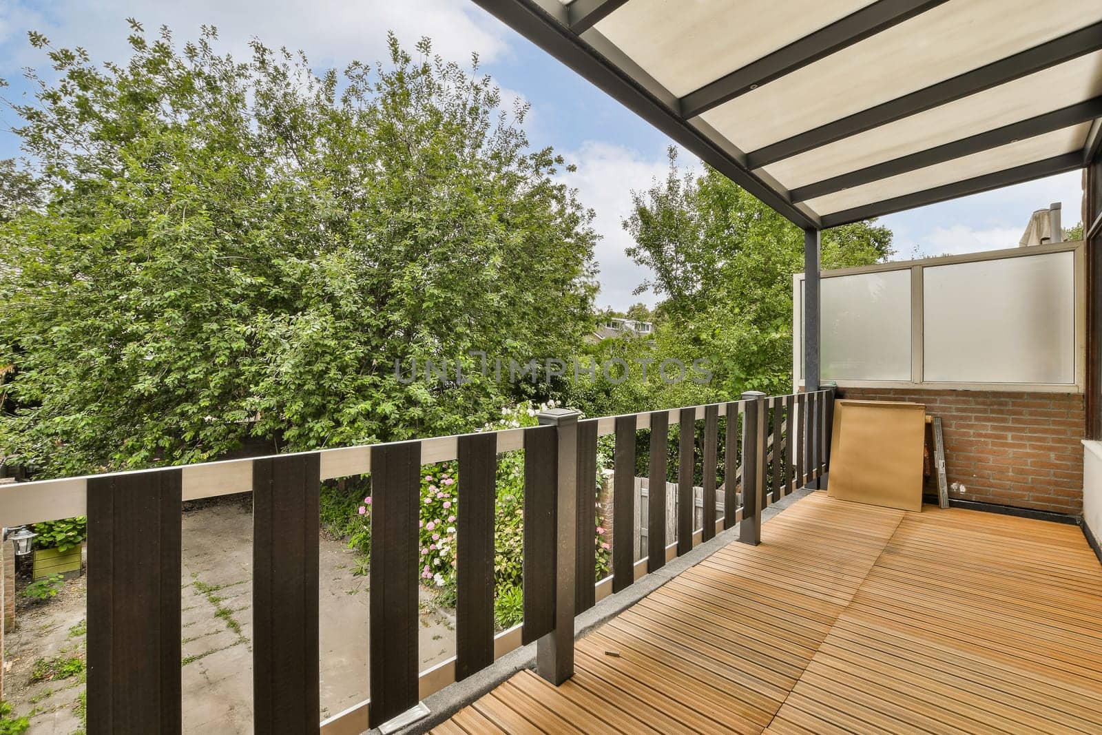 an outside area with wood flooring and wooden fenced in front of the house, surrounded by lush green trees