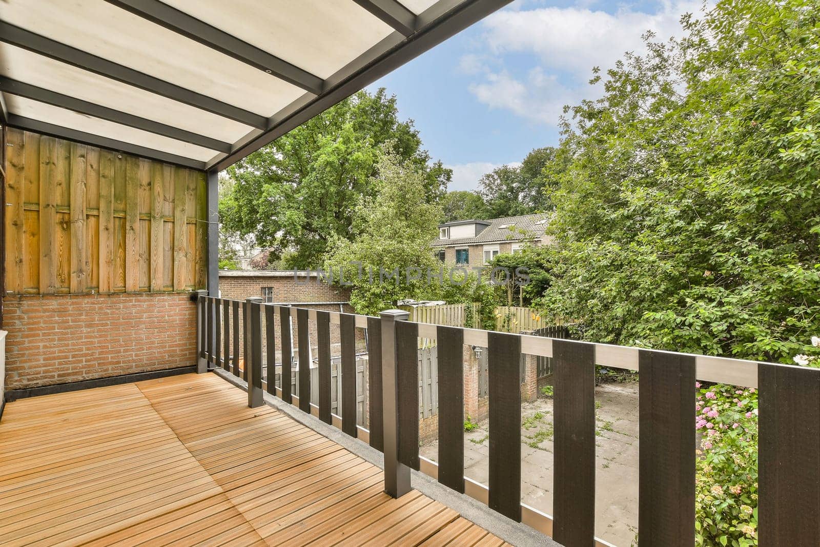 an outside area with wood flooring and wooden fenced in front of the house, surrounded by lush green trees