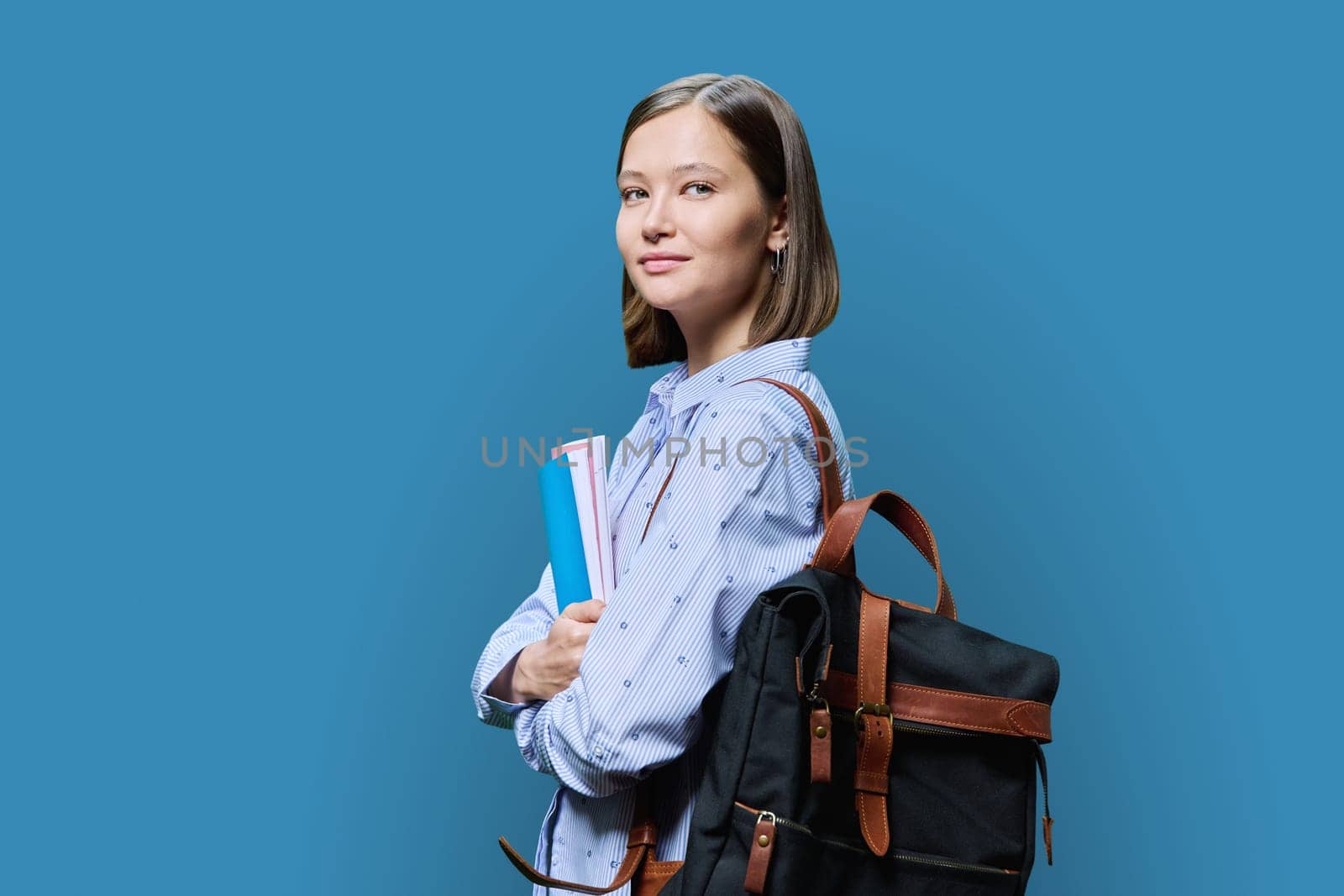 Portrait of young university female student on blue background by VH-studio