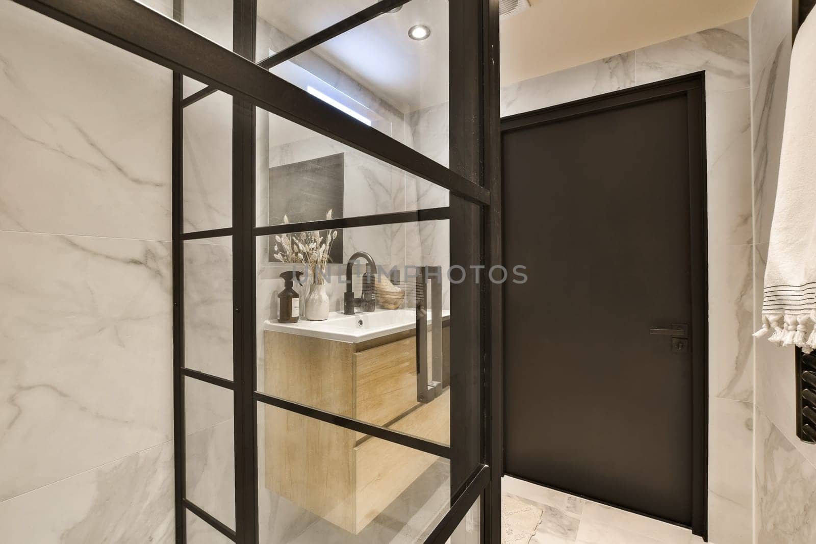 a bathroom with white marble walls and black trim around the shower door, which is open to reveal a large mirror