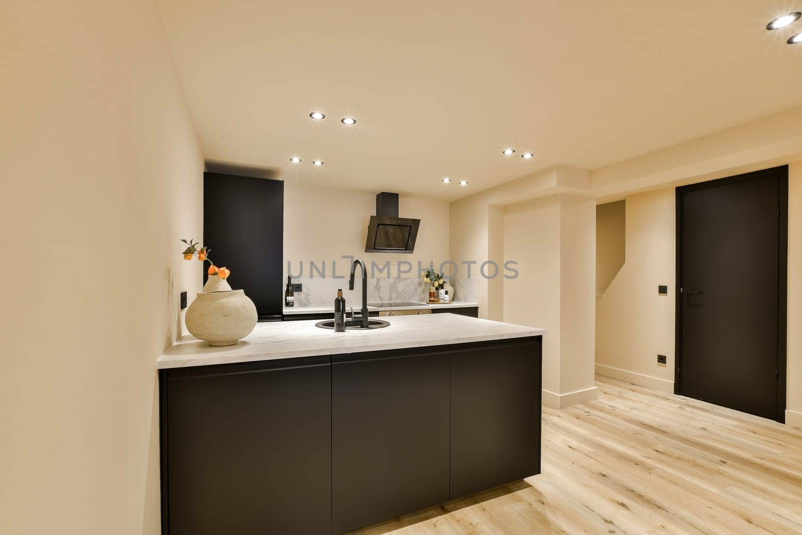 a kitchen with black cabinets and a white counter top by casamedia