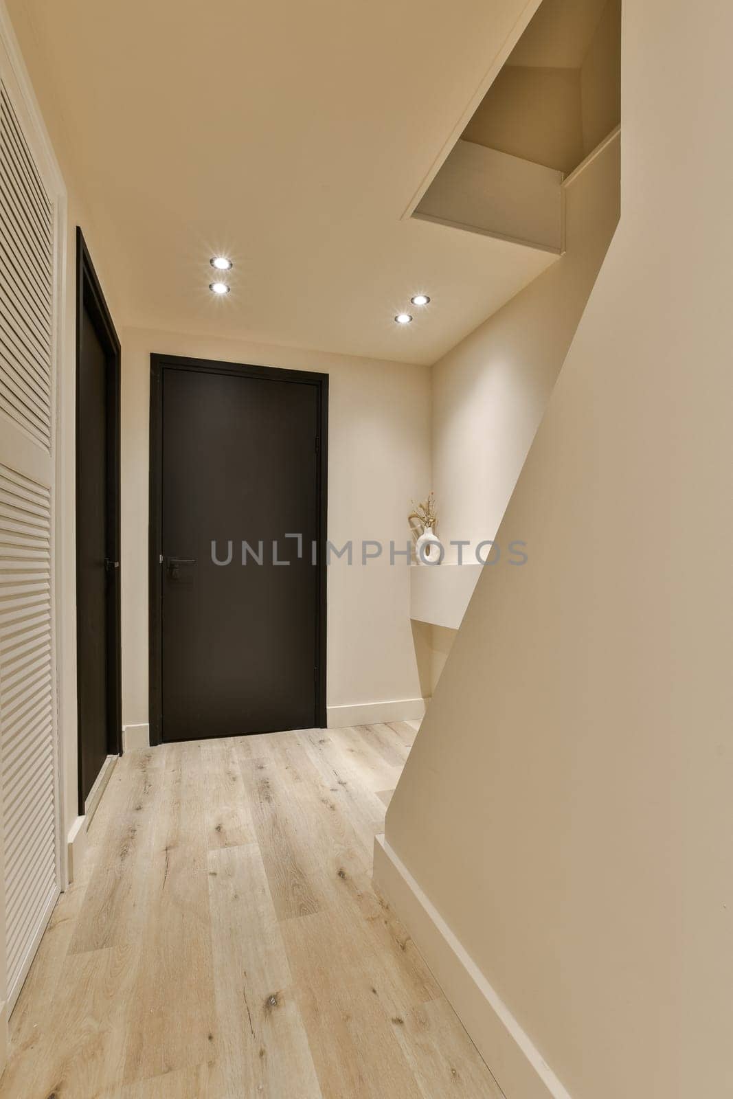 a hallway with a black door and wood flooring by casamedia