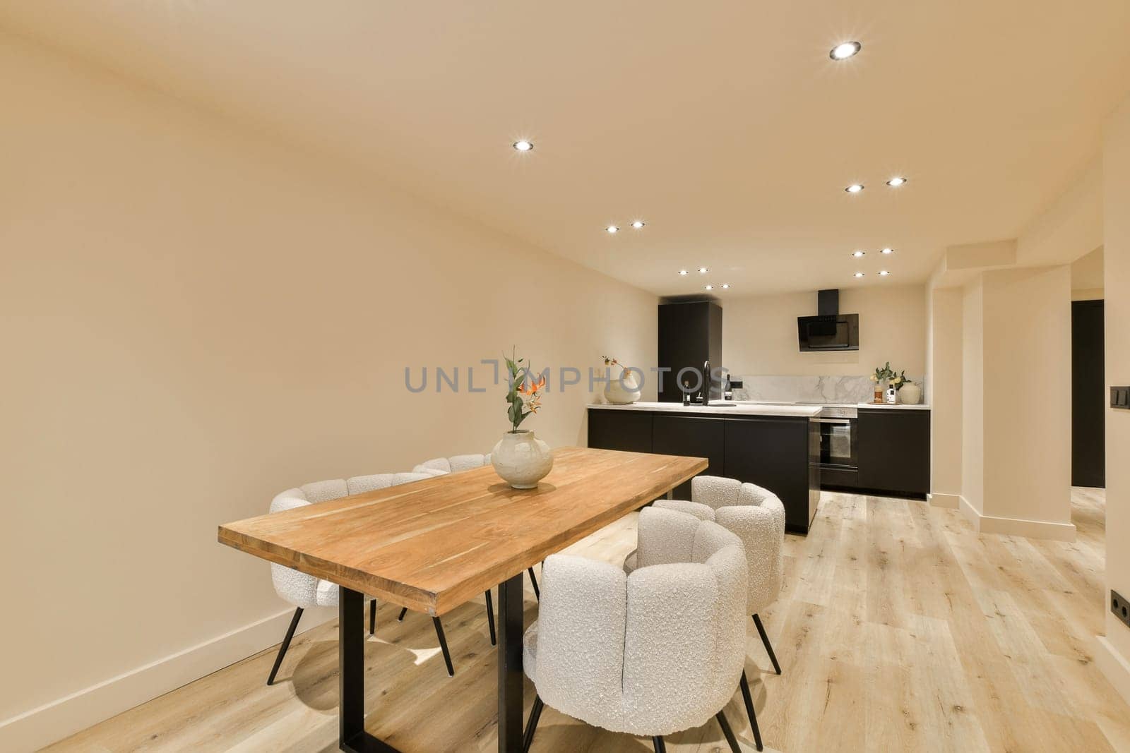 a kitchen and dining area in a house with white walls, hardwood flooring and light wood table surrounded by chairs