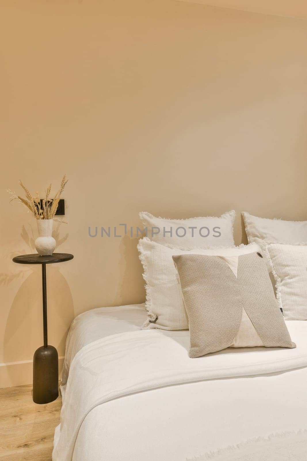 a white bed with pillows and a black table by casamedia