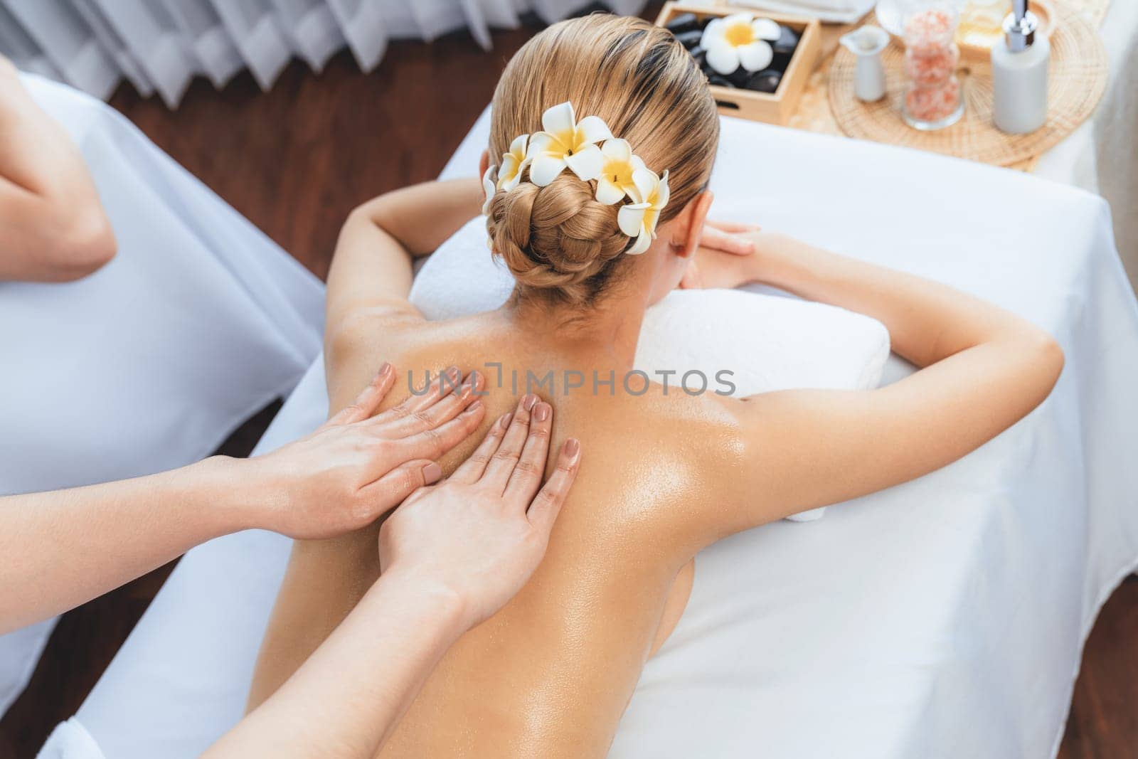 Caucasian couple customer enjoying relaxing anti-stress spa massage and pampering with beauty skin recreation leisure in day light ambient salon spa at luxury resort or hotel. Quiescent