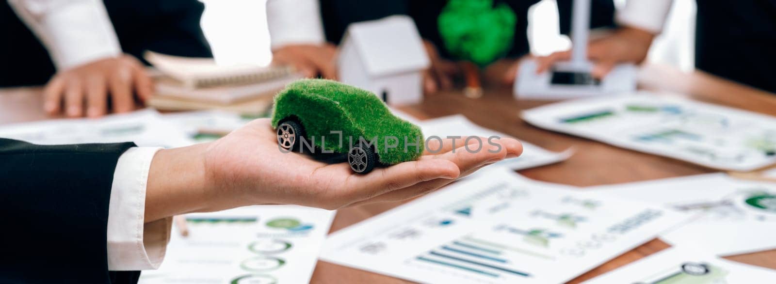 Businessman holding green EV car model mock in electric car company meeting, business people planning strategic marketing for eco-friendly vehicle product using clean energy with net zero.Trailblazing