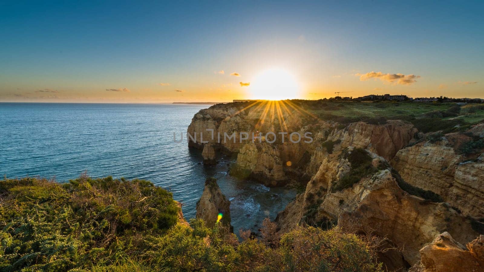 Sunset over the cliffs and beaches by Atlantic Ocean, Lagos, Algarve, Portugal.