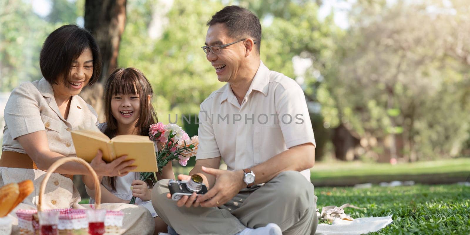 happy smiling family grandparent and grandchild picnic together outside at park by itchaznong