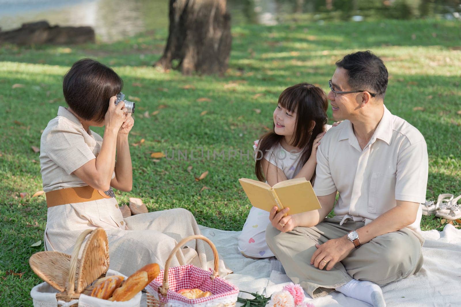 happy smiling family grandparent and grandchild picnic together outside at park by itchaznong