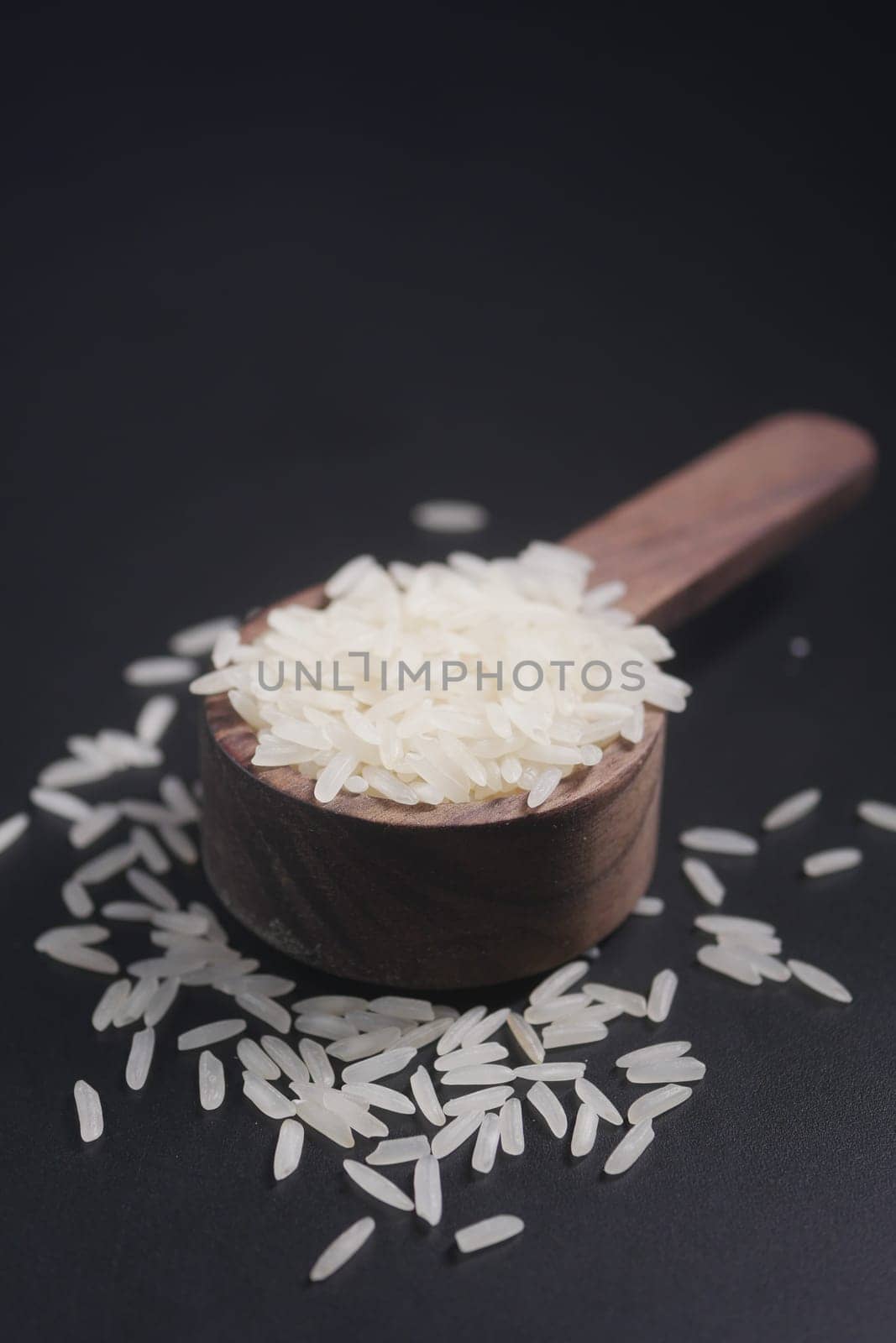 Raw white rice on a wooden spoon .