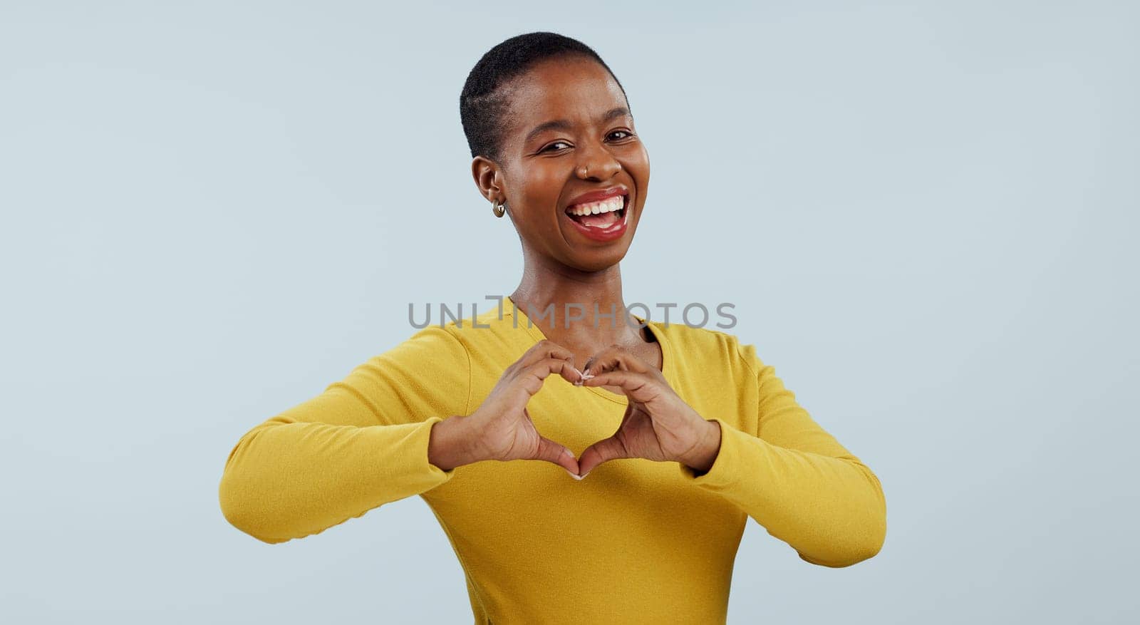 Happy black woman, portrait and heart hands for love, care or romance against a gray studio background. Face of African female person or model showing like emoji, shape or romantic gesture on mockup.