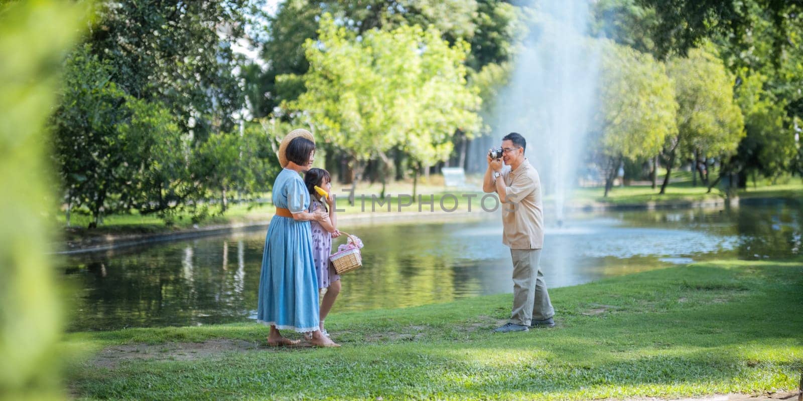 Grandpa takes pictures of granddaughter and grandma with his in park on sunny day happiness. concept grandparent and grandchild family lives together happy.