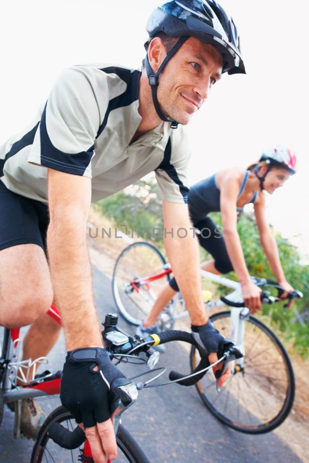 Happy, couple and cycling on road in nature for cardio, fitness and training on bicycle together. Outdoor, people and exercise on bike for fun, workout and travel in countryside adventure or journey.