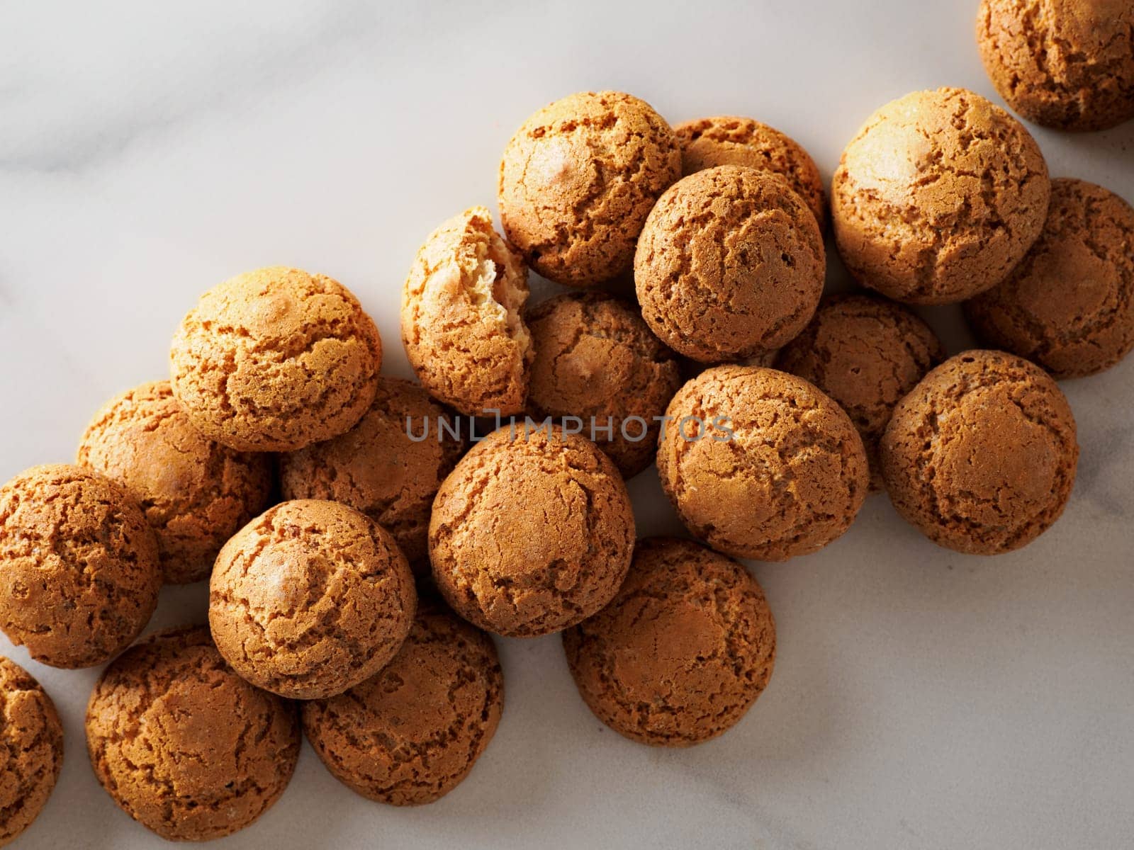 pile of cookie amaretti on white marble background - traditional Italian Sardinian pastry. Delicious amaretti biscuit cookies made from almond or apricot kernels with copy space