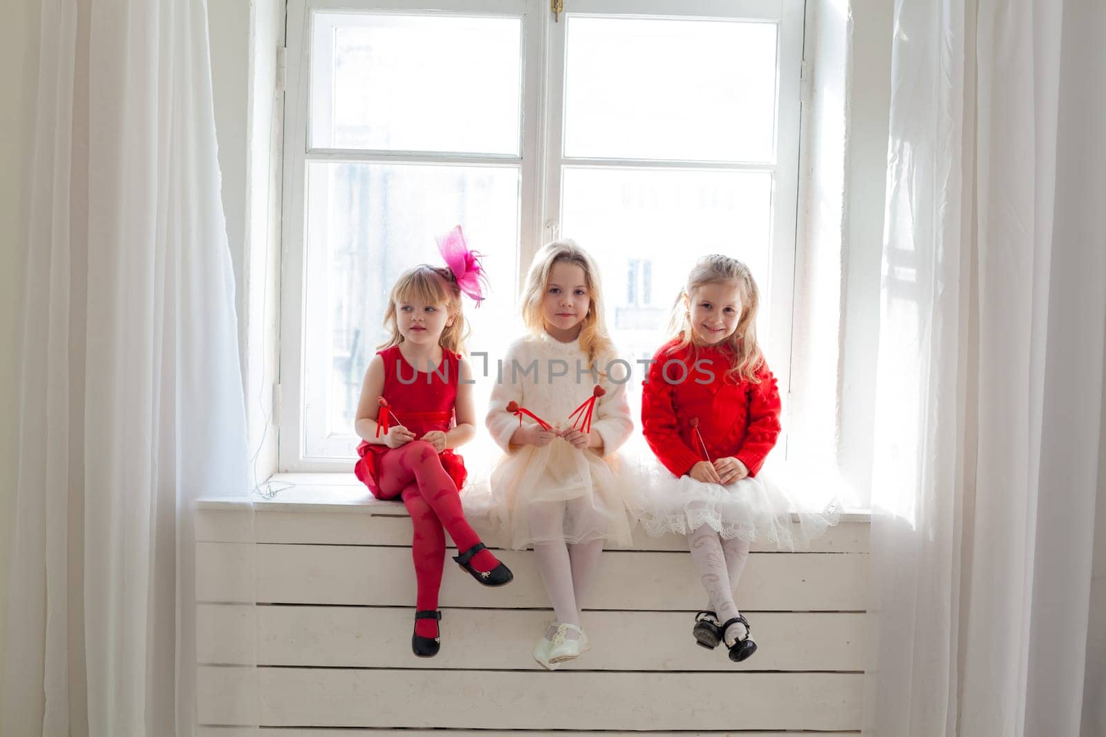 a three girls sitting on the windowsill in the room