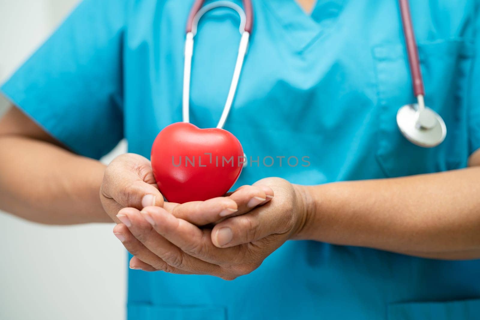 Doctor holding a red heart in hospital ward, healthy strong medical concept.