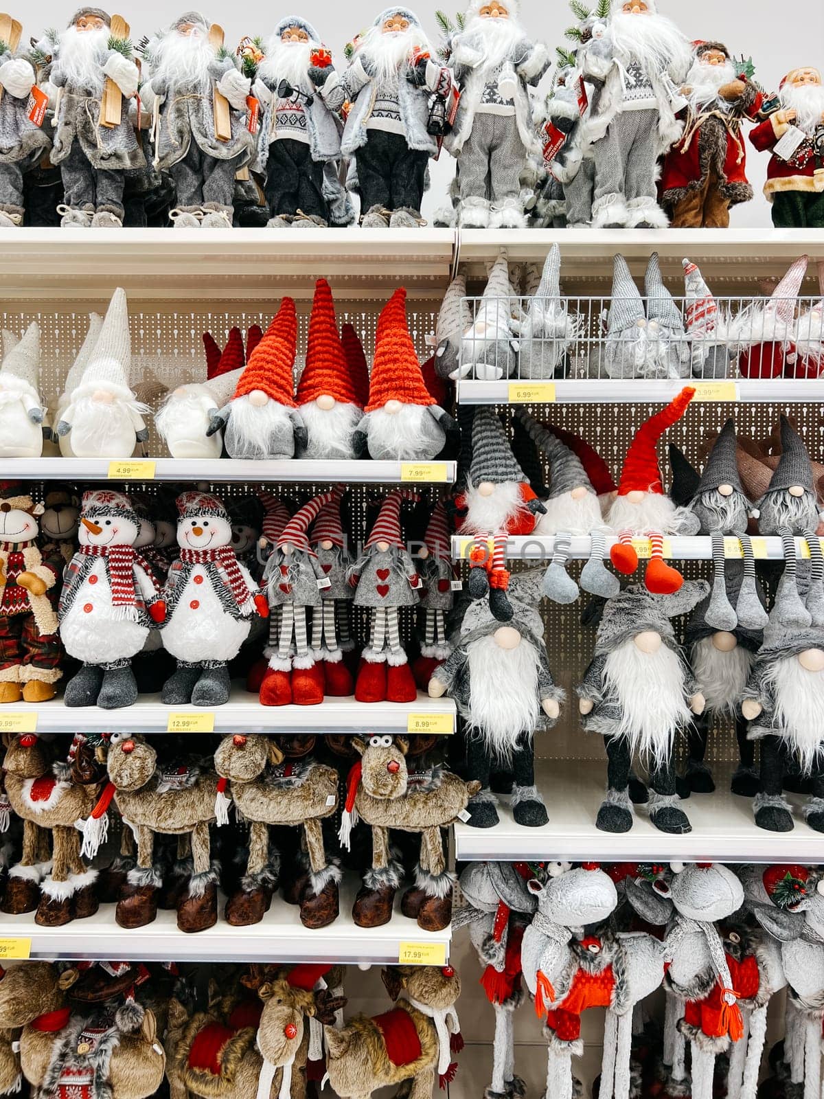 Multi-colored figurines of Santa Claus, gnomes and deer are on the shelves of the store. High quality photo