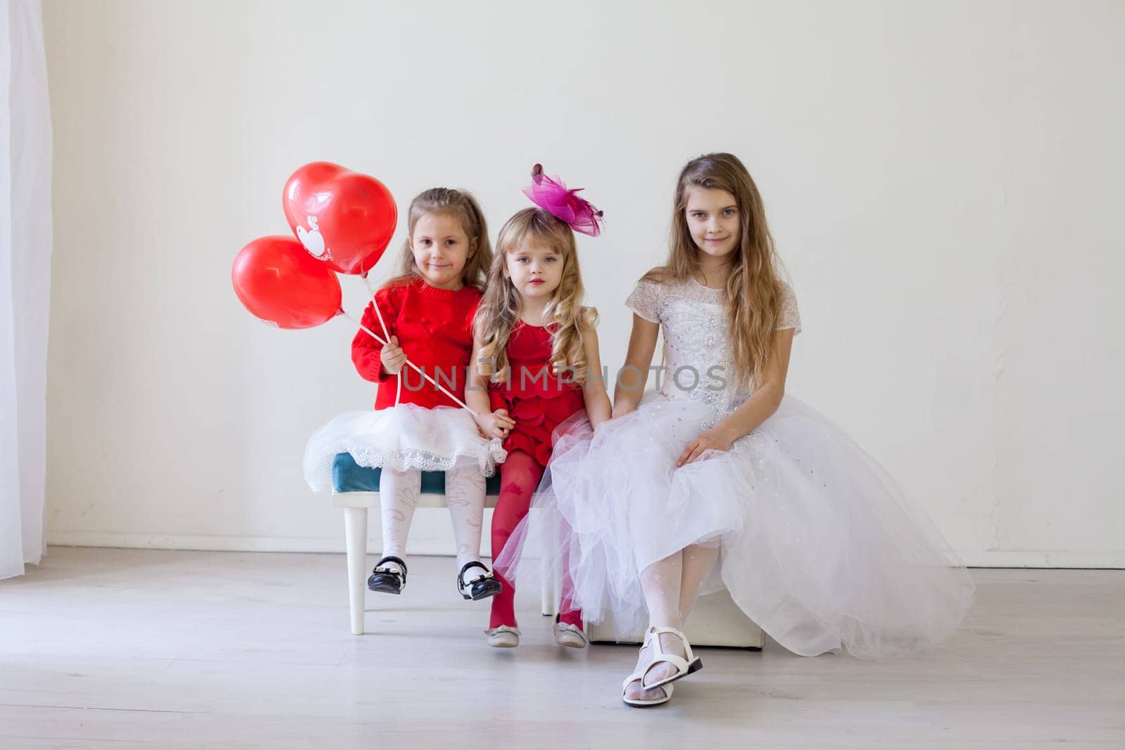 a three children with red balloons sitting in a holiday room