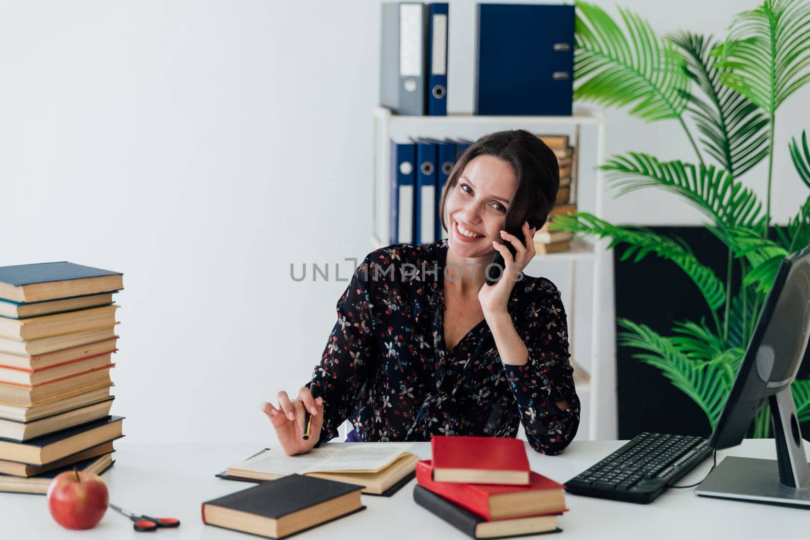 business woman office worker speaks on the phone in the office with a book at the desk in the office by Simakov