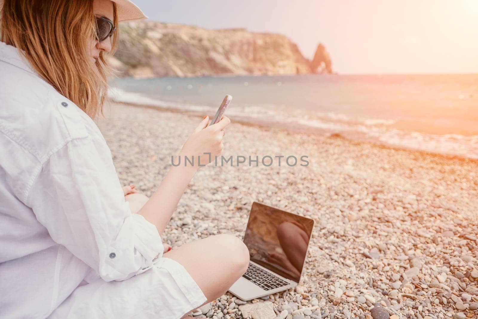Woman sea laptop. Business woman in yellow hat working on laptop by sea. Close up on hands of pretty lady typing on computer outdoors summer day. Freelance, digital nomad, travel and holidays concept. by panophotograph