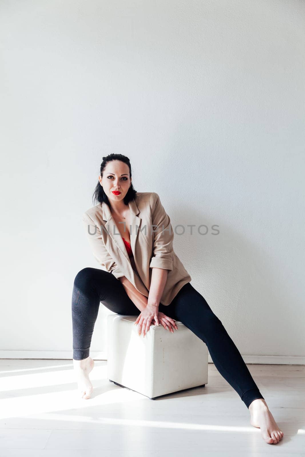 a fashionable brunette woman sitting in a bright room on a white background