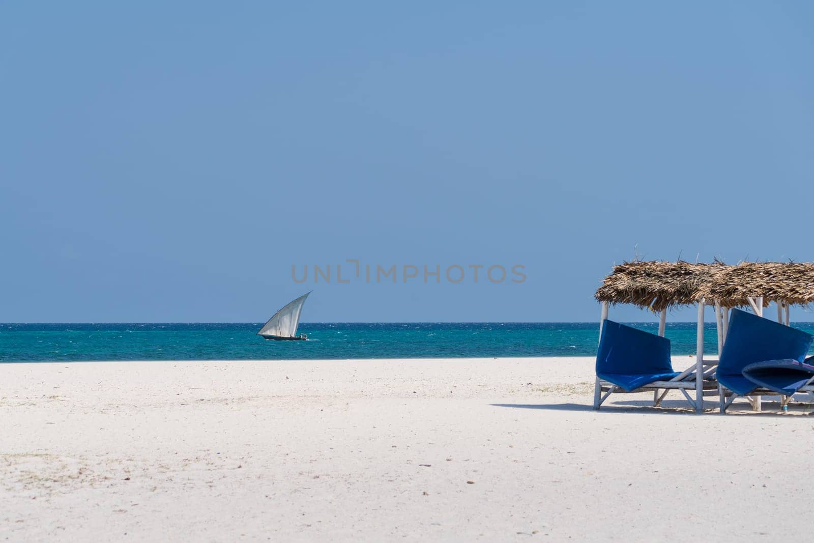 White sandy beach and boat sails in the ocean at sunny day by Robertobinetti70